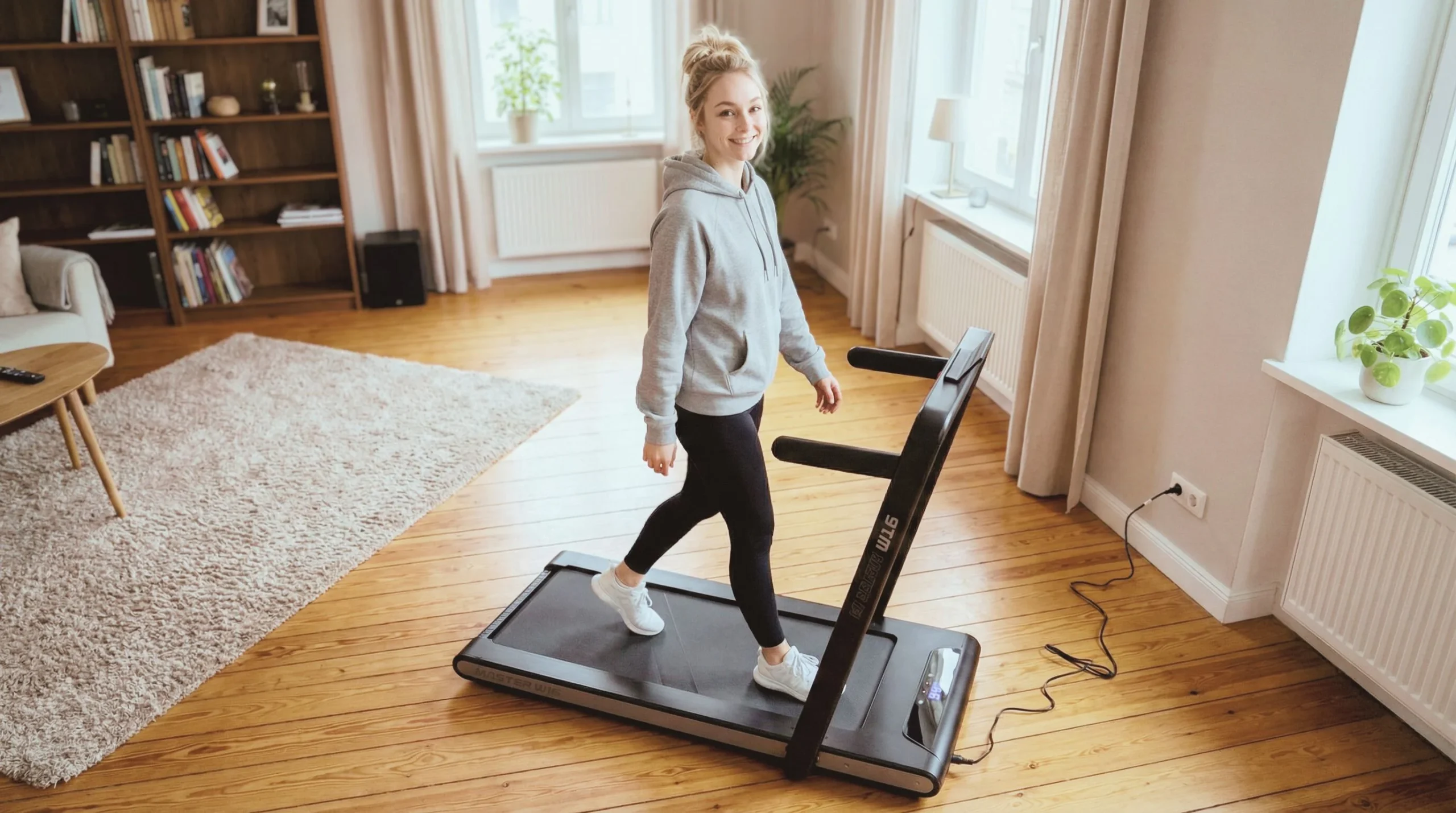 En kvinna går på Master Fitness W16 gåband hemma