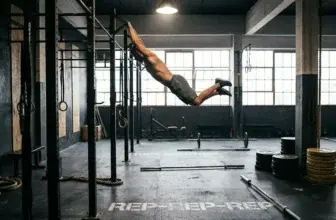 En atletisk person i sportkläder hänger i ett pull-up-stång inomhus på ett CrossFit-gym