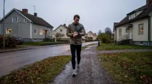 Nybörjarlöpare kollar tiden på löparklockan under ett lugnt joggingpass på en grusväg