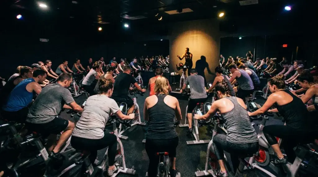 Ett fullsatt spinning-pass sett bakifrån med instruktören längst fram på podiet.