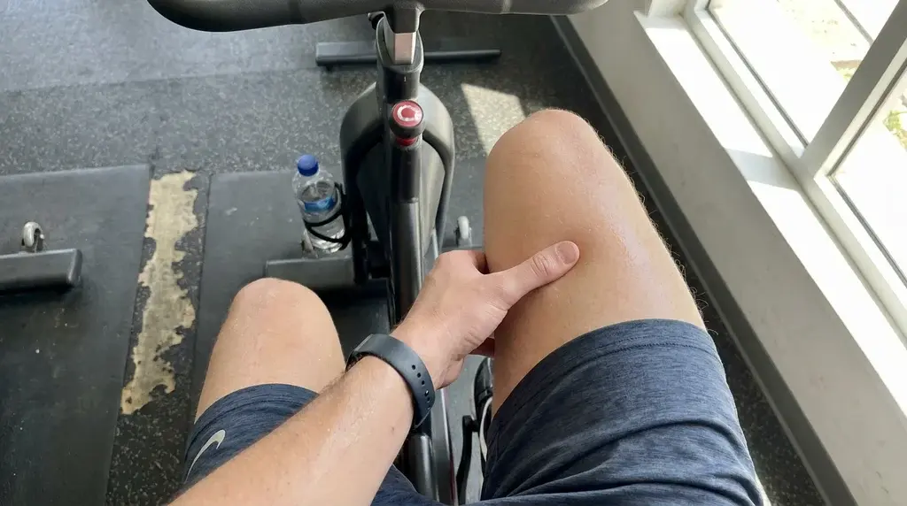 Cyklist känner efter på ömma lårmuskler efter ett spinningpass